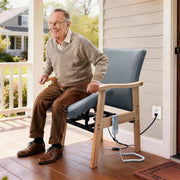 Senior using gray power lift chair for assisted standing near a home entrance